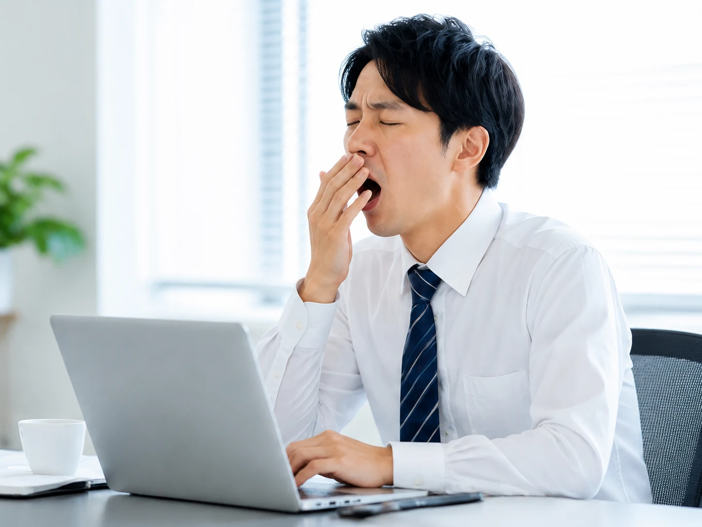 日中に強い眠気であくびをするビジネスマン