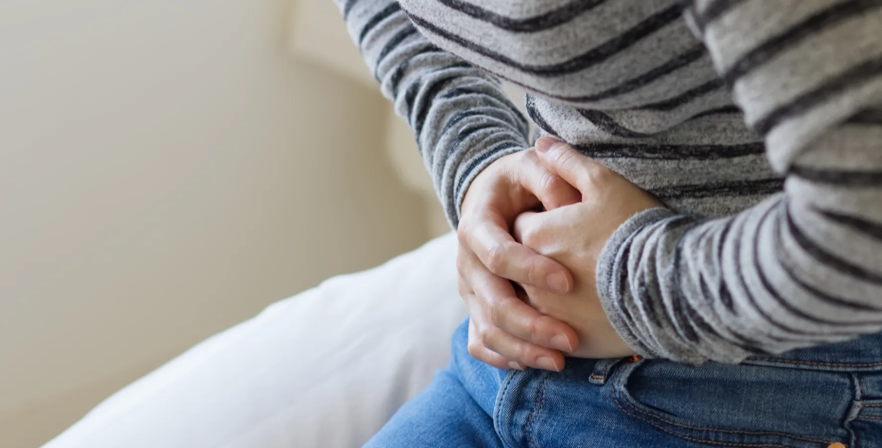 お腹を押さえて便意を我慢する女性